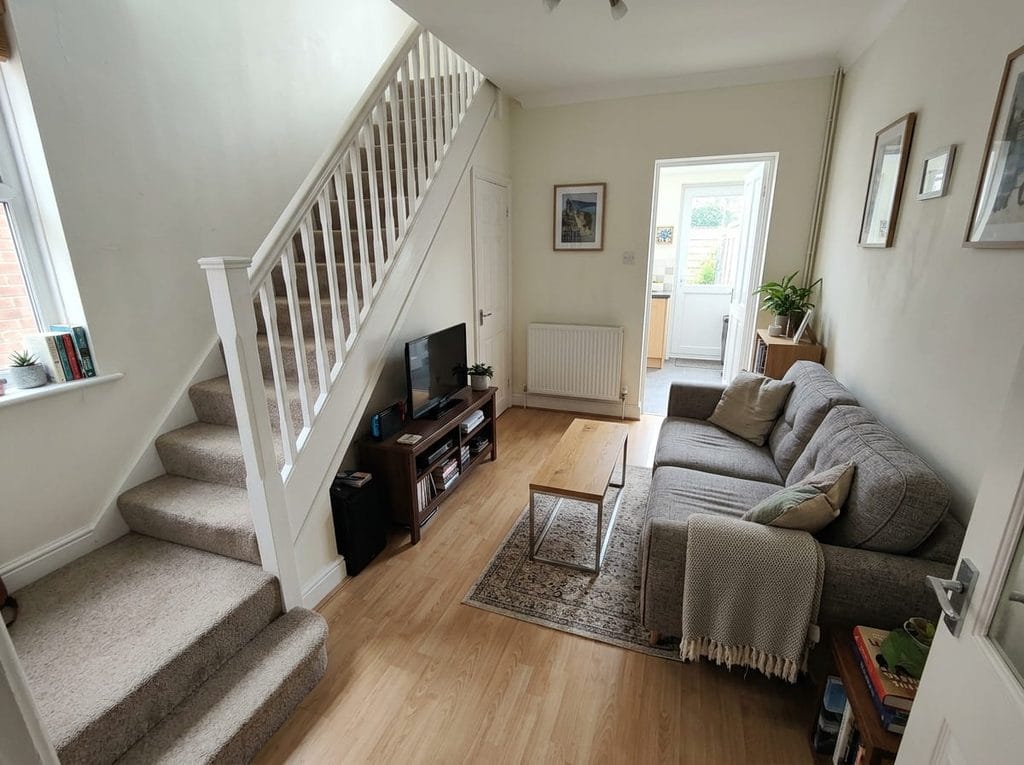 Compact sofa positioned parallel to stairs in a small living room